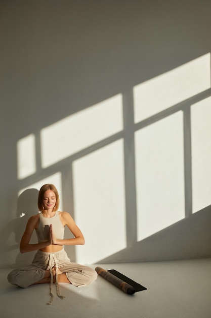 Foto donna che pratica yoga e meditazione in postura di loto su un tappetino da yoga rilassata meditazione consapevole