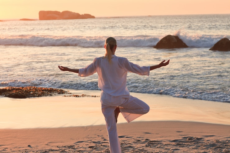 Photo woman practicing yoga during the sunset at the beach