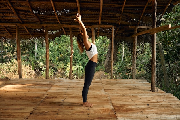 Женщина, практикующая йогу в тропической открытой студии йоги