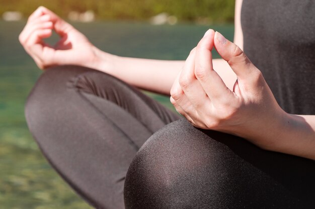 Woman practising yoga or meditating near the lake on the nature