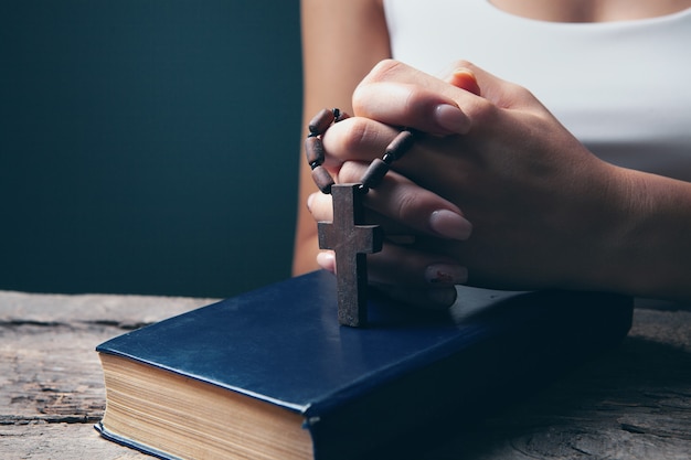 Donna che prega su un libro con in mano una croce