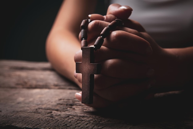 Woman praying on book holding cross