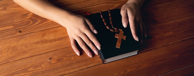 Donna che prega su un libro con in mano una croce