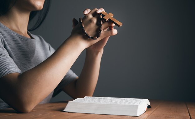 Photo woman praying on a book and holding a cross