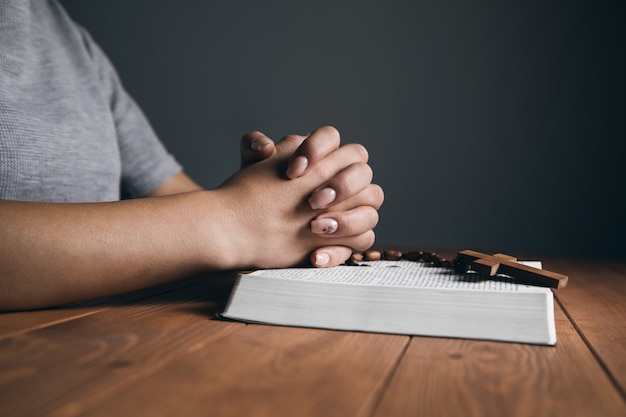 Woman praying on a book with a cross