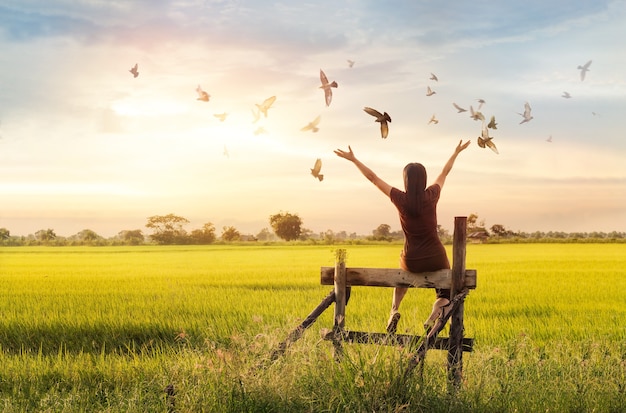 Woman praying and free bird enjoying nature on sunset background, hope concept 