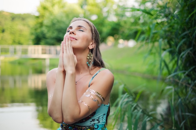 Woman praying portrait at green nature during beautiful sunset