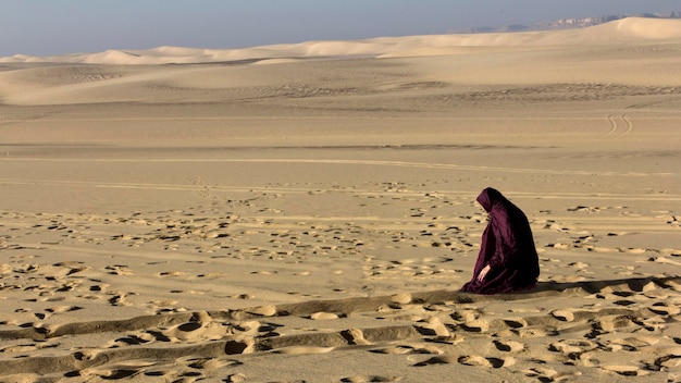 Foto donna che prega sulla sabbia nel deserto