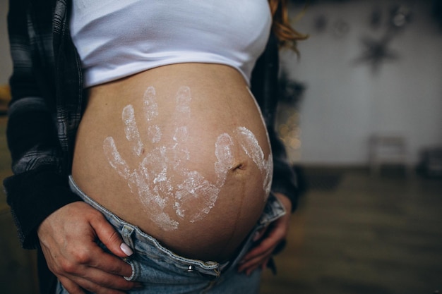 Woman pregnant belly with child prints in shirt and blue jeans