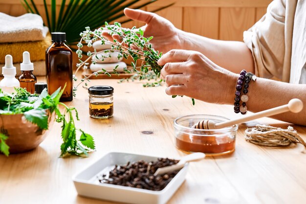 Donna prepara una sessione di aromaterapia con diffusore di oli essenziali, erbe medicinali, oli e essenze