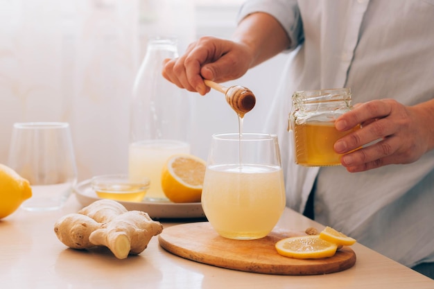 Woman prepares drink from fresh ginger root lemon honey Health antioxidant herbal vitamins