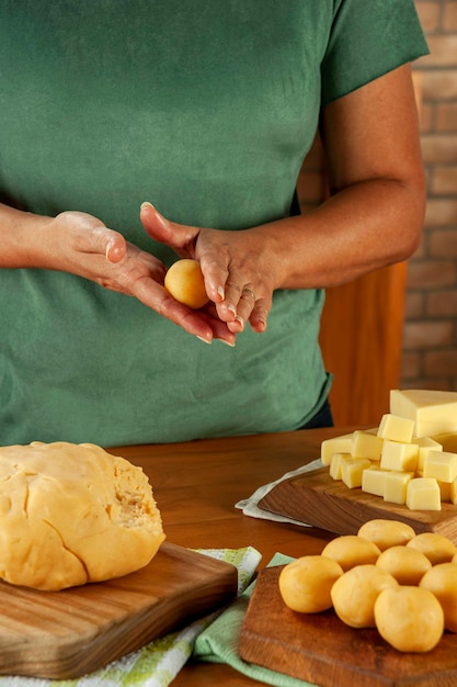 Woman preparing brazilian cheese stuffed croquette bolinha de queijo on a wooden table