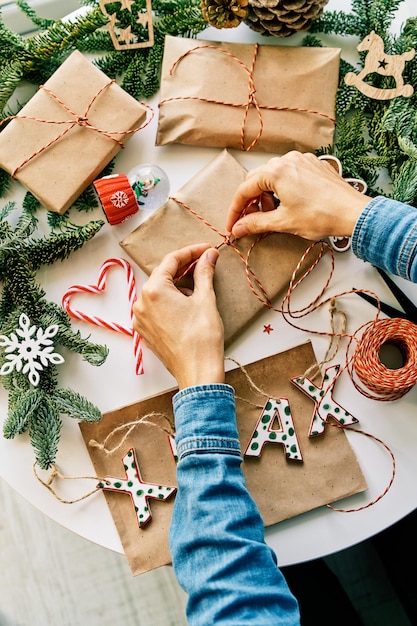 Woman preparing christmas gifts with rope and christmas decorations