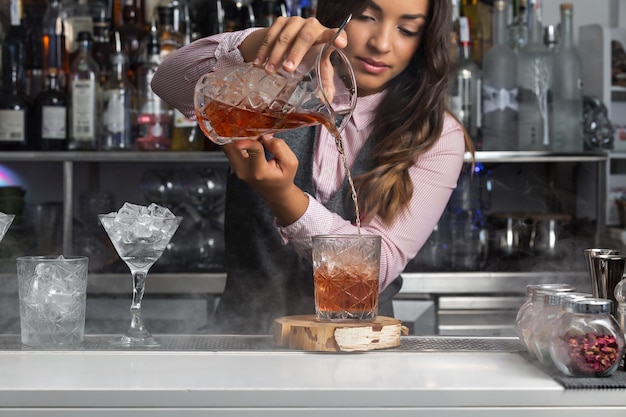 Woman preparing cocktail at bar counter