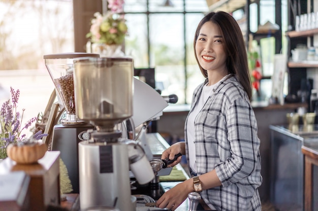 Woman preparing coffee with machine in cafe