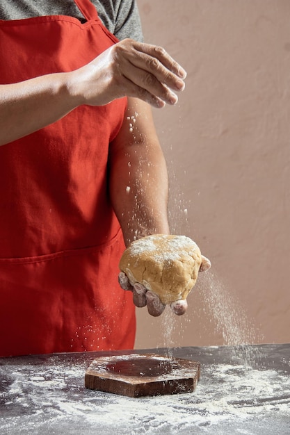 Woman preparing dough for homemade cookies at kitchen table in cupboard