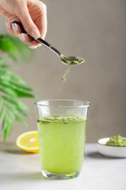 Woman preparing drink with green superfood powder. immunity support.