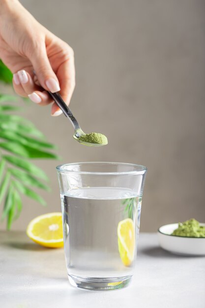 Woman preparing drink with green superfood powder