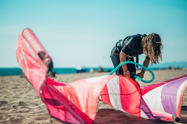 Donna che prepara l'aquilone da kiteboarding con la pompa dell'aria