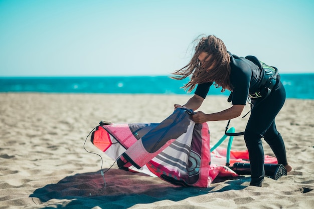 Woman preparing kiteboarding kite with the air pump