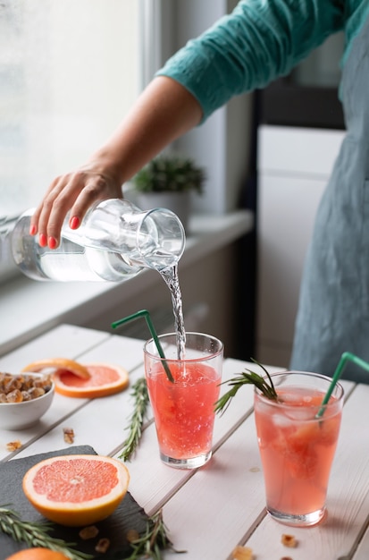 woman preparing lemonade at home. Cooking in kitchen. female hands.