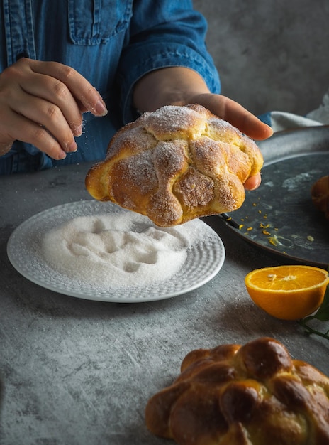 Woman preparing Pan de muertos bread of the dead for Mexican day of the dead