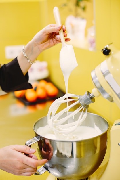 Woman preparing pastries. Confectioner in a coat.