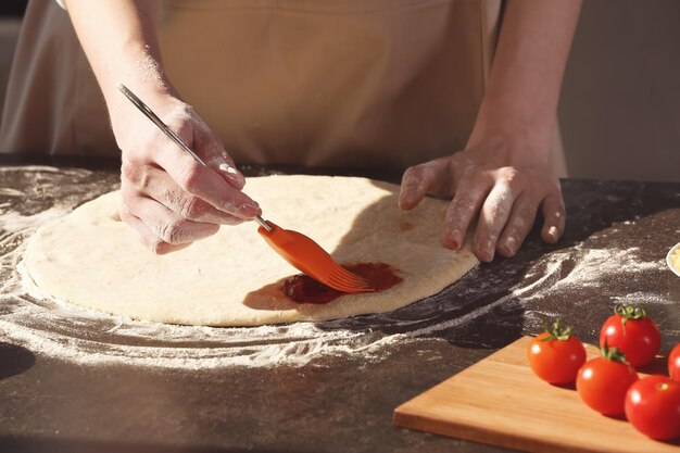 Photo woman preparing pizza at kitchen table