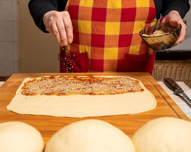 Woman preparing sweet roll cake with jam