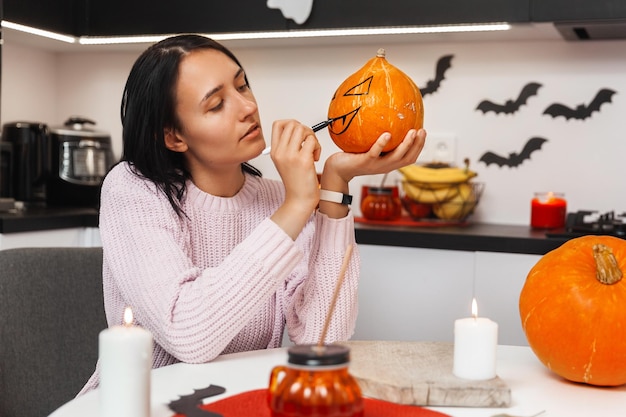 Donna che si prepara per halloween e dipinge zucche in cucina