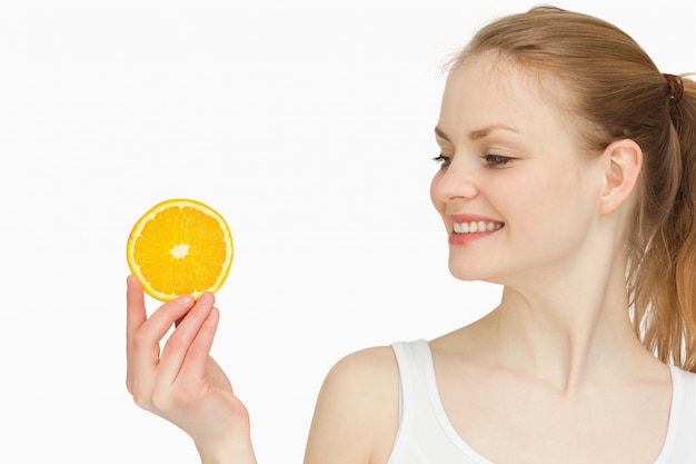 woman presenting an orange slice while looking at it