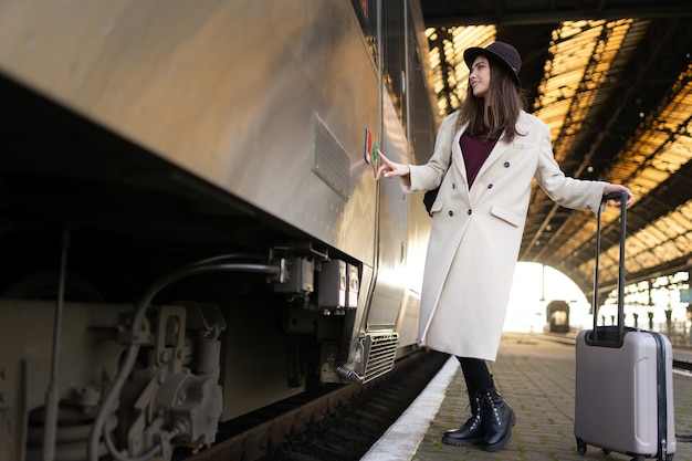 女性が電車のドアのボタンを押して入る