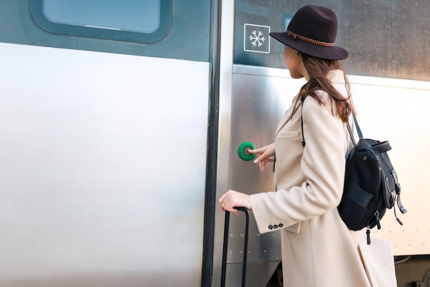 女性が電車のドアのボタンを押す