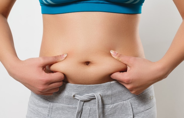 The woman presses her fingers to the folds of fat on the sides of her stomach