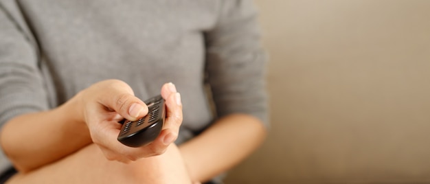 Photo woman presses online tv remote at home