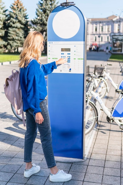 写真 女性がターミナルボタンを押してシティバイクを借りる