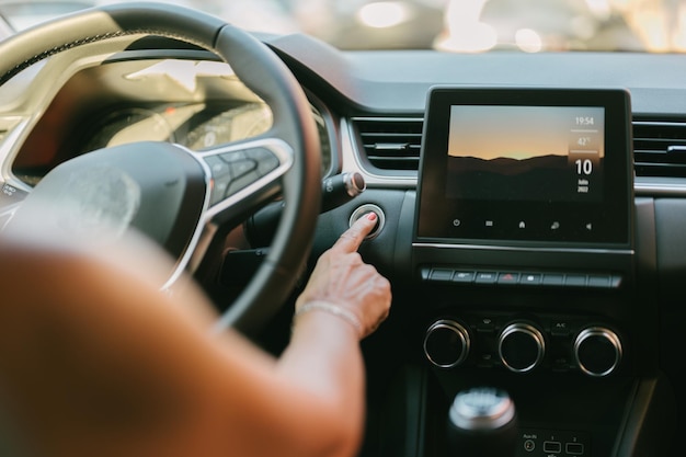 Woman pressing the automatic start button on her car