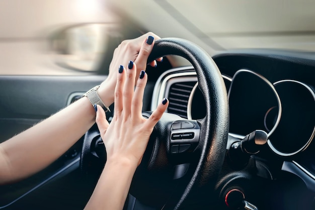 Donna che preme il pulsante clacson sul volante mano femminile che suona il clacson durante la guida di un'auto