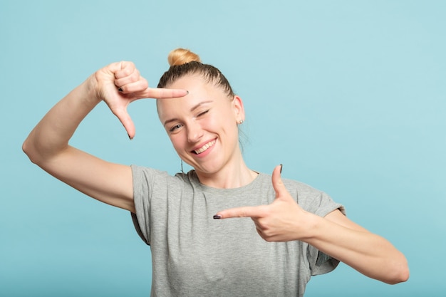 フレームを作成する彼女の手を通して写真を撮るふりをしている女性。写真の趣味とレジャー。