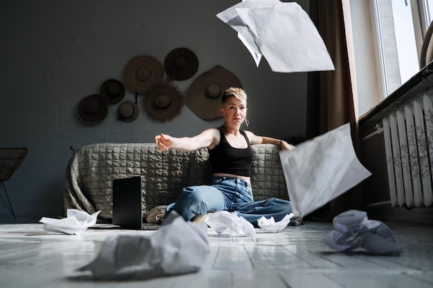 Woman professional content writer working with papers and laptop computer at home while sitting on