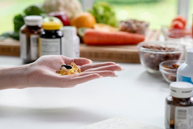 Женщина-профессиональный диетолог проверяет пищевые добавки в руке в окружении различных фруктов, орехов, овощей и пищевых добавок на столе