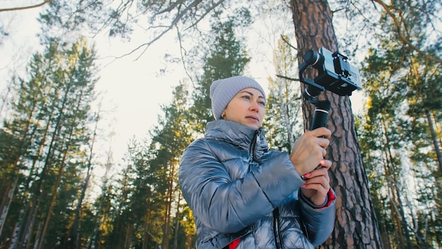 The Woman Professional Videographer Holding Smartphone on 3axis Gimbal Stabilization Device in Winter Pro Equipment Helps to Make High Quality Video on Phone Cinematographer Operator Slow Motion