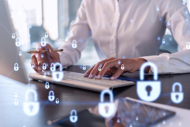 A woman programmer is typing a code on computer to protect a\
cyber security from hacker attacks and save clients confidential\
data padlock hologram icons over the typing hands formal wear