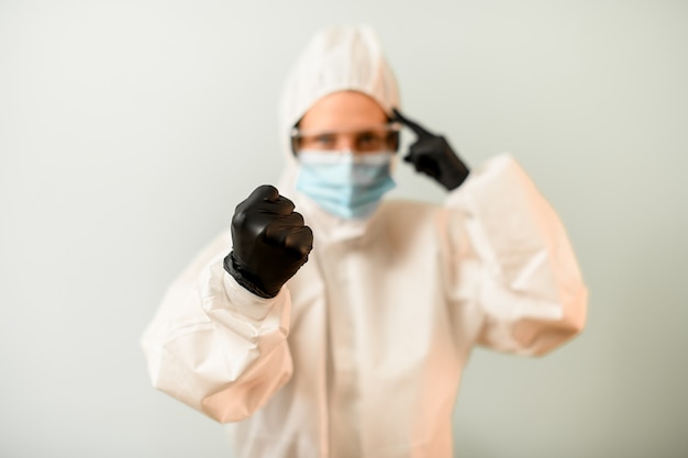 Woman in protective clothes shows fist and points to head