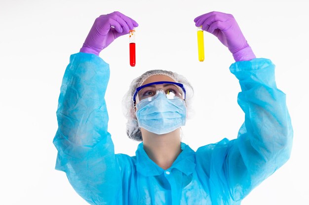 The woman in a protective coat is comparing two tubes with different liquid in her hands with gloves