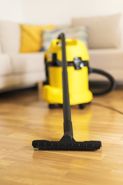 Woman in protective gloves cleaning the living room with yellow vacuum cleaner. Clean concept