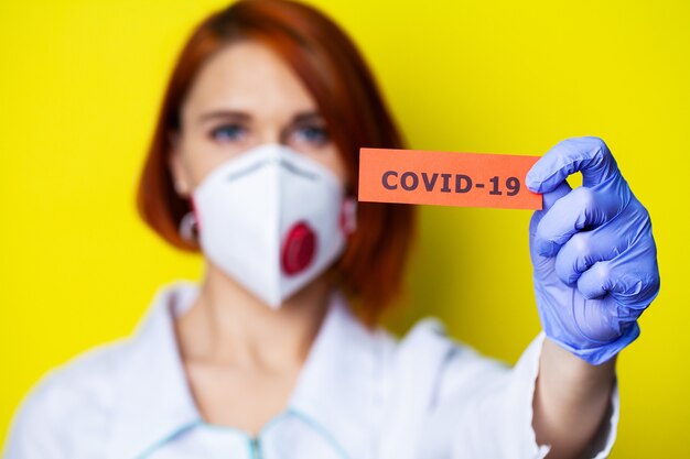 Woman in protective gloves holding inscription coronavirus