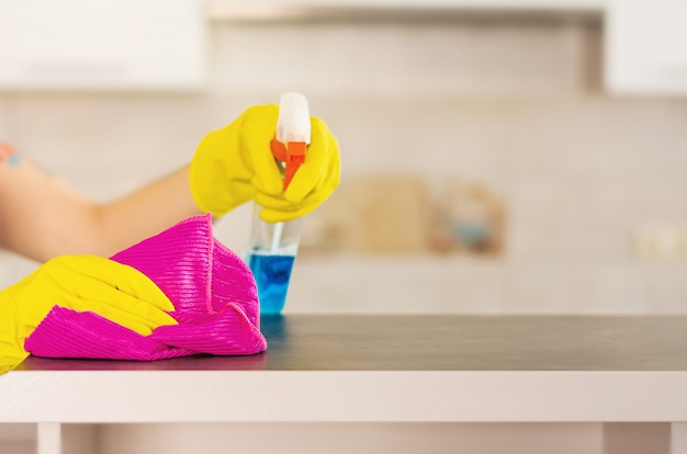 Woman in protective gloves wiping dust using cleaning spray and duster. cleaning service concept