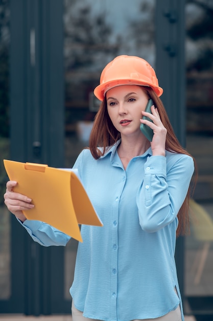 Woman in protective helmet communicating by smartphone