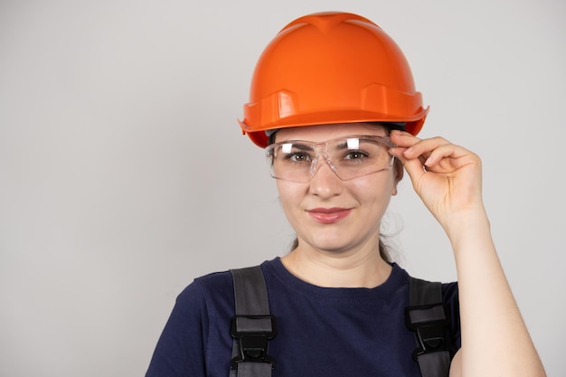 Photo a woman in a protective helmet glasses and overalls on a white background with space for text